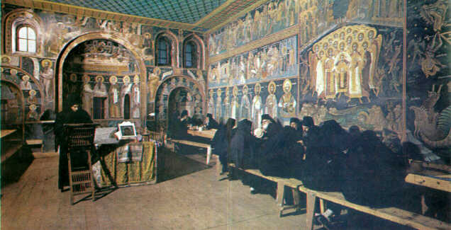 Η τράπεζα της Μονής Διονυσίου.  Στην αψίδα είναι η θέση του καθηγουμένου, ενώ σε επιμηκή ξύλινα τραπέζια κάθονται οι μοναχοί.